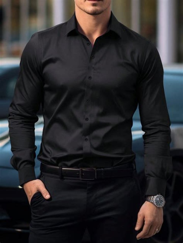 a man in black shirt and jeans standing on one leg with his hands out